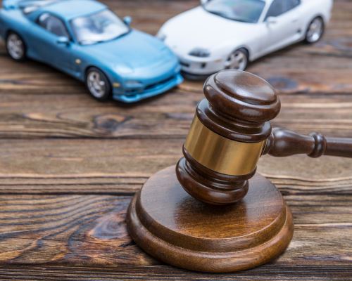 a gavel on a table with two toy cars crashing