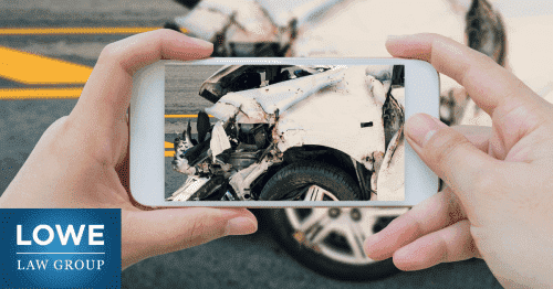 person taking picture of damage to a vehicle after a car accident