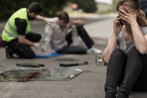 Woman on the phone sitting at an accident scene 